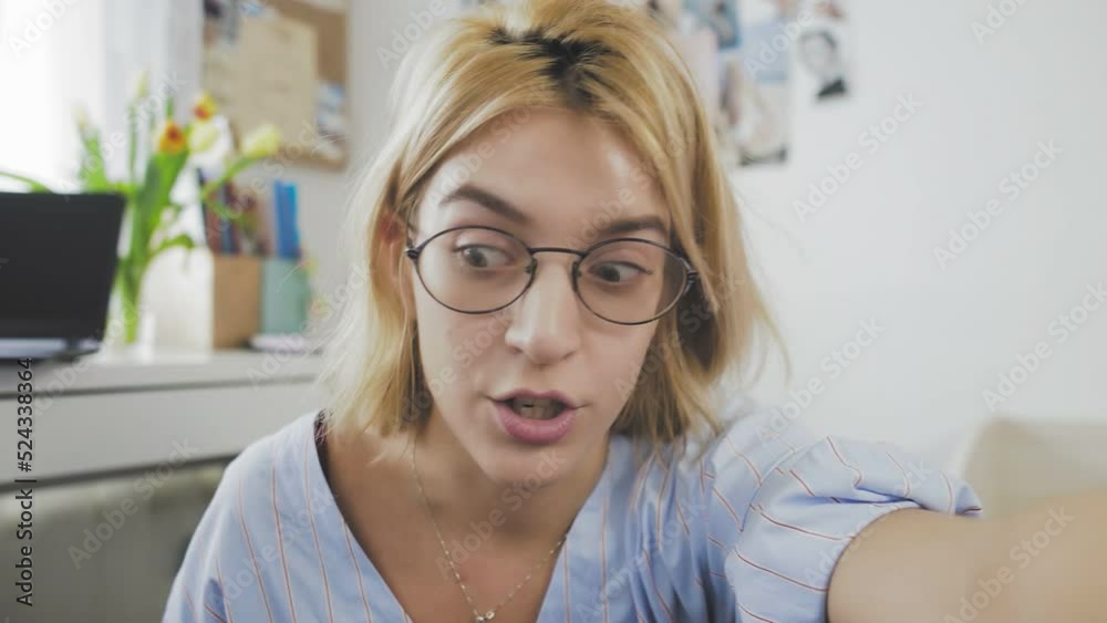 A young beautiful female blogger using a camera recording smiles and talks to the camera