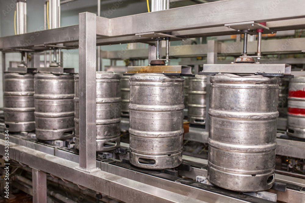Brewery, bottling beer on aluminum kegs on conveyor lines. Industrial work, automated modern food and beverage production. Brewery, bottling beer on aluminum kegs on conveyor lines. Industrial work, automated modern food and beverage production.