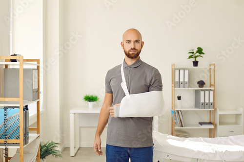 Portrait of young Caucasian man with splint on arm after accident or trauma. Male patient with bandage or sling on hand or shoulder struggle with injury have rehabilitation. Recovery and rehab. photo