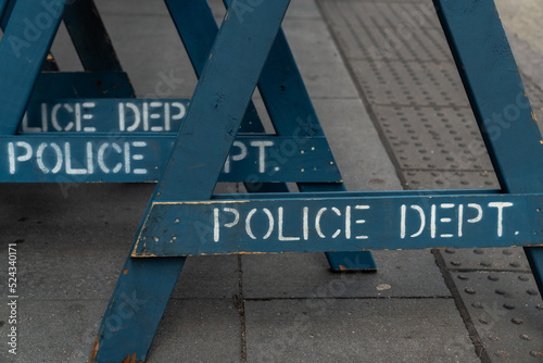Close up view of several stacked weathered and worn blue wooden road barricade A-frame legs with Police Department written on them as they sit on a concrete sidewalk in New York City. photo