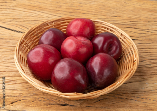 Plums in a basket over wooden table