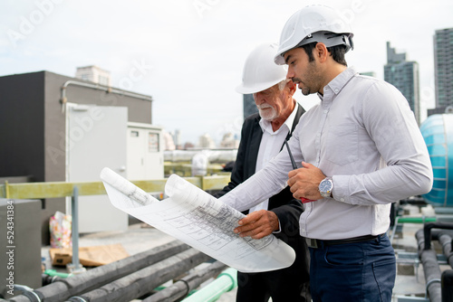 Close up shot young and senior engineer man work together using building plan or drawing in workplace of construction site. © narong