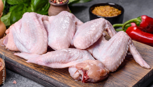 Raw chicken wings with ingredients for cooking on a wooden cutting board