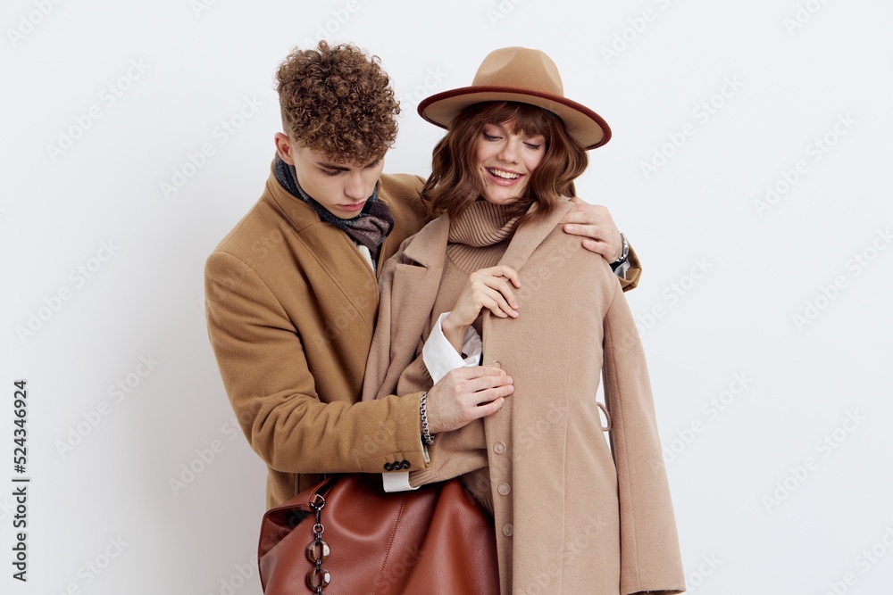 a sweet, joyful, pleasant stylish couple stands on a white background in autumn coats and gently hug each other, a man holds a woman by the coat looking at her a sweet, joyful, pleasant stylish couple stands on a white background in autumn coats and gently hug each other, a man holds a woman by the coat looking at her