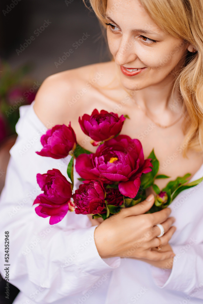 tenderness. a blonde woman in a white shirt and a bouquet of peonies. tenderness. a blonde woman in a white shirt and a bouquet of peonies.