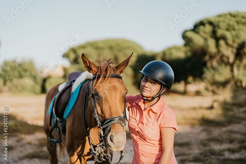 portrait of green-eyed girl rider standing next to her pony