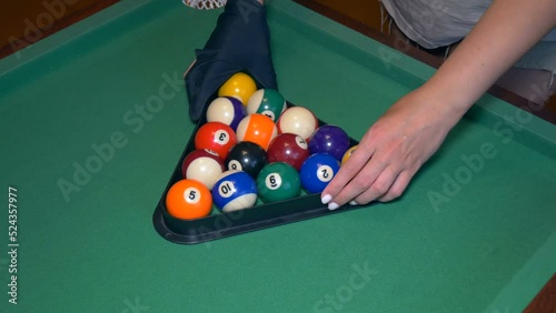 Girl billiard player moves and levels the pyramid of balls. Girl is going to play American pool. 15 balls take part in the game. photo