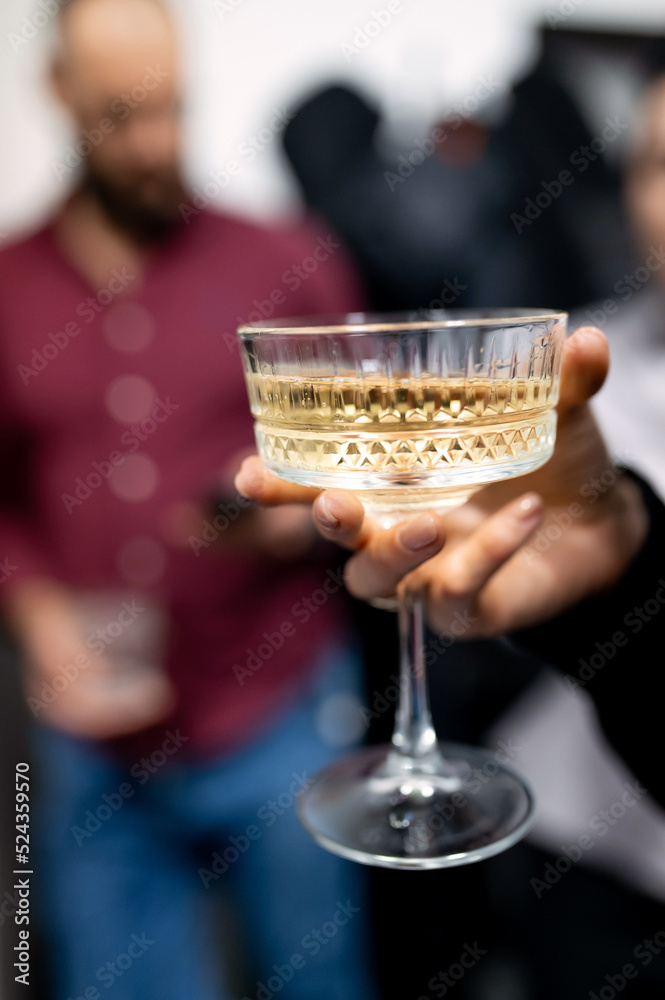 female hand holding a glass of white sparkling champagne