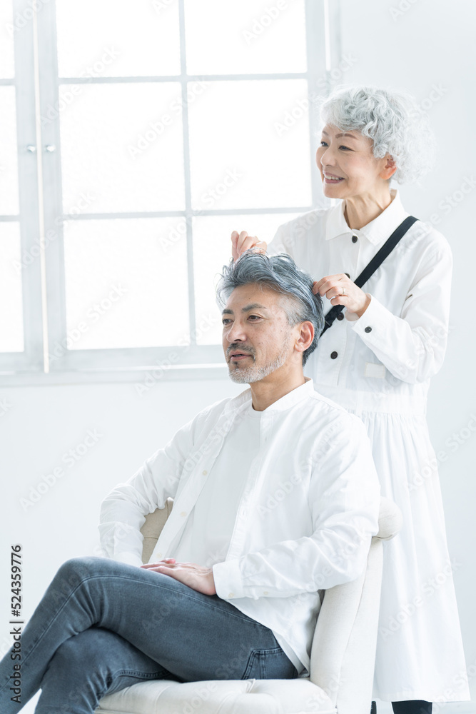 Obraz premium 美容院で働く美容師とヘアセットされるシニア男性（美容・仕事）