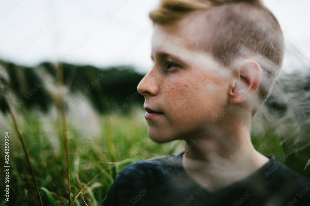 Pre teenage boy outside in nature in grass field Pre teenage boy outside in nature in grass field