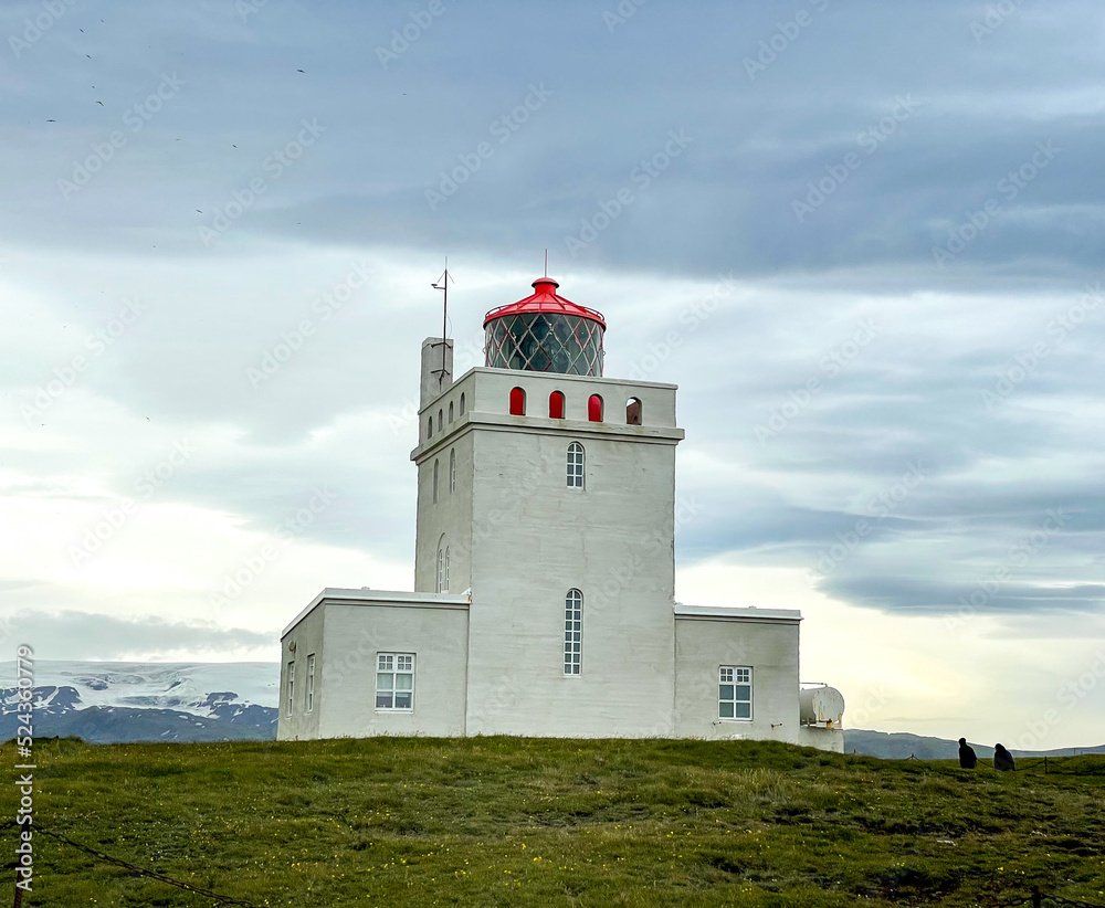 Vik, Iceland - July 3, 2022 View of the Dyrhólaey Lighthouse, a square concrete tower, painted white with red trim, located on the central south coast of Iceland.