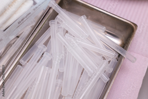 Close-up of used syringes with pink caps laying on metal  medical tray. Facial needles for thread lifting procedure. cosmetology procedure photo
