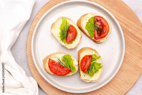 Bruschetta sandwich bread toast with soft white cheese ricotta fresh tomatoes basil greenery on a wooden cutting board.Tasty healthy vegetarian food Italian cuisine appetizer. top view flat lay