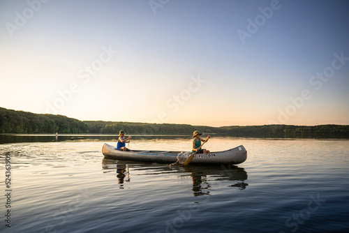 Obraz na plátně Air Force service member takes his sons canoeing at sunset out on the lake