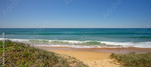 Fotografie The Buddina foreshore with grassy vegetation on sand dunes and surf waves breaking on the sea shore