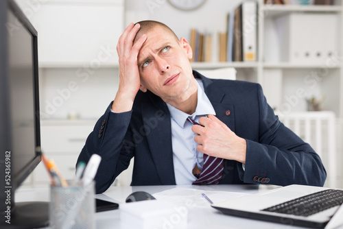 фотографія Male working in the company became stuffy in the office and, loosening the knot on his tie for easy breathing, put his