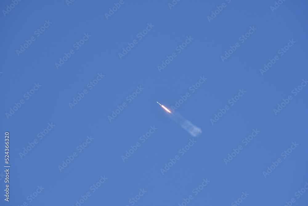 Distant Rocket Launch clear Blue Day with exhaust trail and sunny sky Distant Rocket Launch clear Blue Day with exhaust trail and sunny sky
