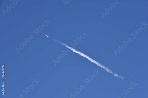 Distant Rocket Launch clear Blue Day with exhaust trail and sunny sky