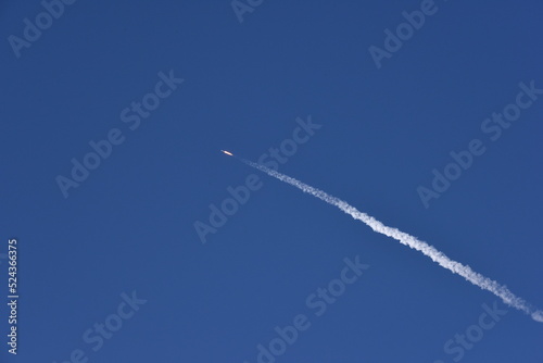 Distant Rocket Launch clear Blue Day with exhaust trail and sunny sky