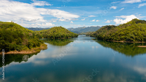 A river among mountains and hills with a reflecting blue sky and clouds. Randenigala reservoir, Sri Lanka.