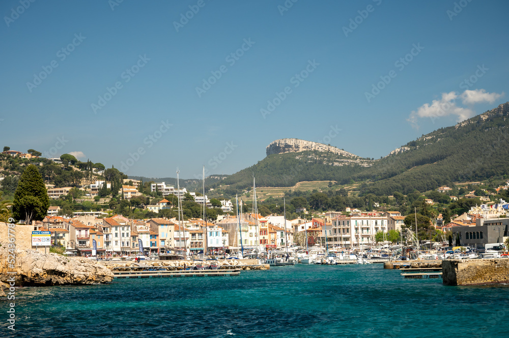 Panoramic view on cliffs, blue sea, beach, houses, streets and old fisherman's harbour with lighthouse in Cassis, Provence, France