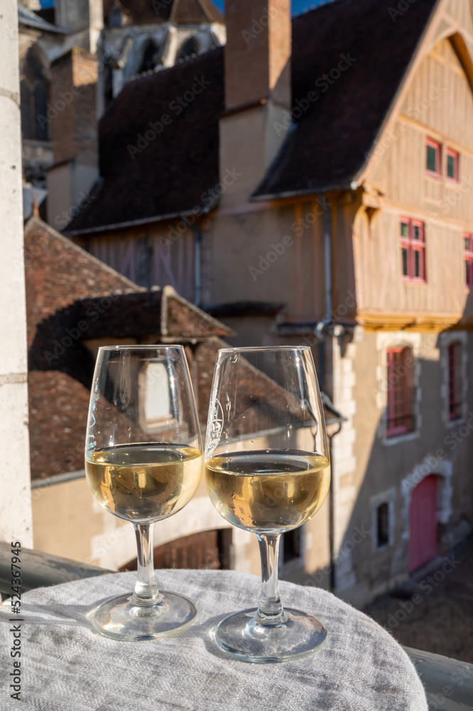 Tasting of white grand cru classe chablis wine with old French houses on background, Burgundy, France