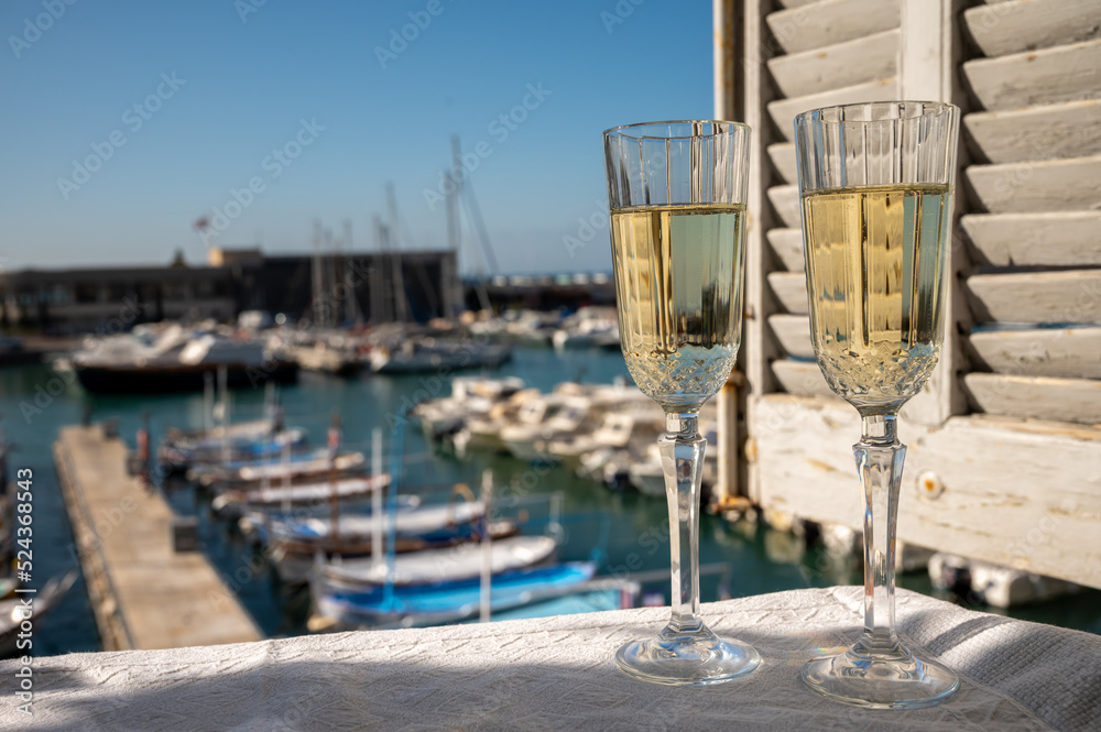 Obraz premium Two glasses of French champagne sparkling wine and view on colorful fisherman's boats in old harbour in Cassis, Provence, France