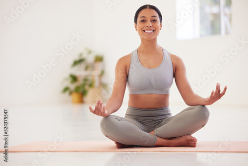 Meditation, yoga and meditating young woman sitting in a lotus pose happy and smiling during a class. Portrait of a fit, mindful and calm female living a healthy lifestyle training at home