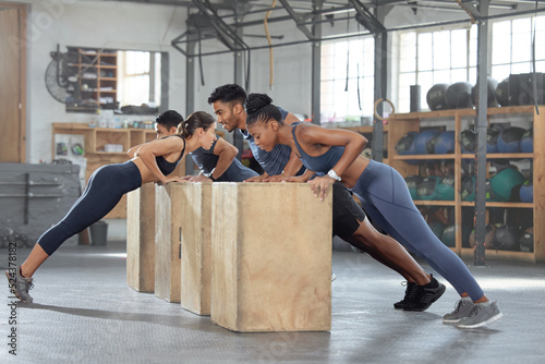 Group training, incline push up and bodyweight exercise, workout and fitness in a gym class with plyometric jump boxes. Sporty, strong and active people with endurance, energy and wellness challenge photo