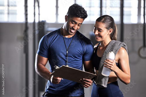 Gym subscription, personal trainer and happy client talking and ready to fill in a membership form. Fitness coach discussing training, workout plan and progress in a health and wellness facility photo