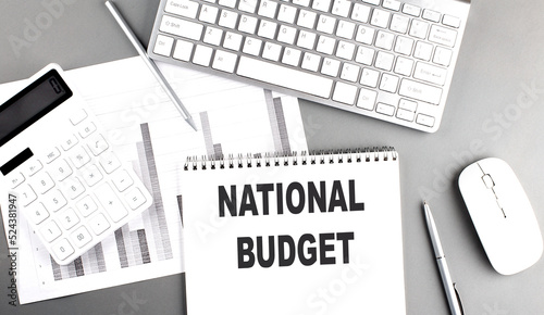 NATIONAL BUDGET text written on notebook on grey background with chart and keyboard , business concept