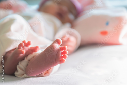 Blur images, foot of baby newborn is 7-day-old is lying on the bed, to children and newborn concept.