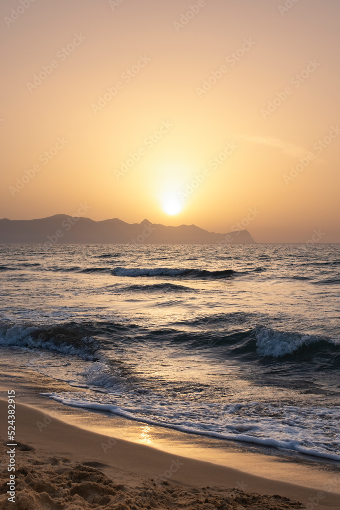 Obraz premium Lido lagoa Balestrate beach. island of Sicily, Italy. Waves against the background of the setting sun. Silhouette of mountains in the background.