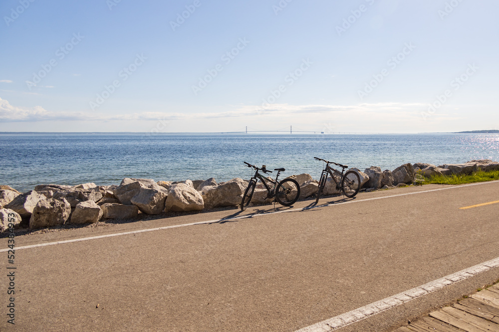 Two bicycles parked on the side of the road with Mackinac Bridge in background