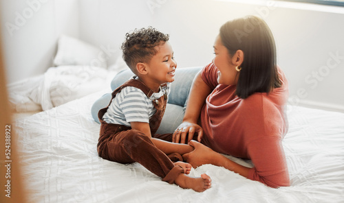 Childcare, love and caring mother playing with toddler son in bedroom, teaching him to talk in a bed room at home. Single parent or mom showing love, affection and care for baby boy, bonding together photo