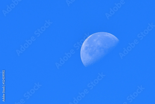 The moon in the morning sun on the blue sky