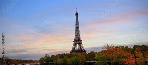 Eiffel Tower, iconic Paris landmark as autumn trees park across the River Seine with tourist boat in sunset sky scene at Paris ,France
