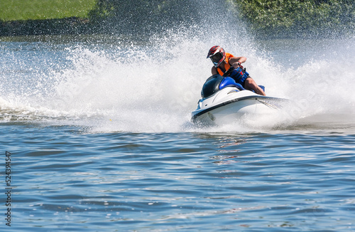 men riding fast jet ski on river. speed and water spray.