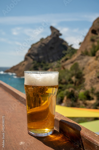 Glass of fresh cold lager beer served outdoor in snack bar with view on Calanque de Figuerolles in La Ciotat, Provence, France
