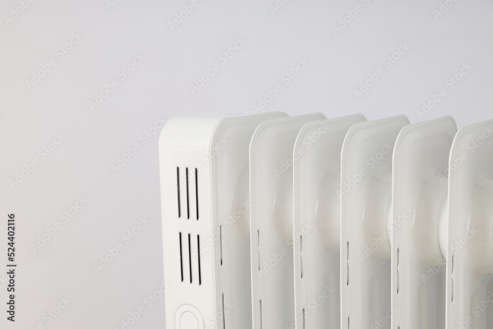 Modern white electric heater against light background