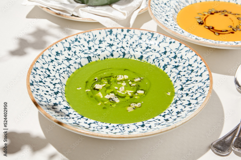 Composition with vegetable soup in ceramic bowl. Green soup with broccoli and cheese on summer day. Italian soup with green pea. Vegan menu. Hot dishes. Vegetables food. Eat less meat. Composition with vegetable soup in ceramic bowl. Green soup with broccoli and cheese on summer day. Italian soup with green pea. Vegan menu. Hot dishes. Vegetables food. Eat less meat.
