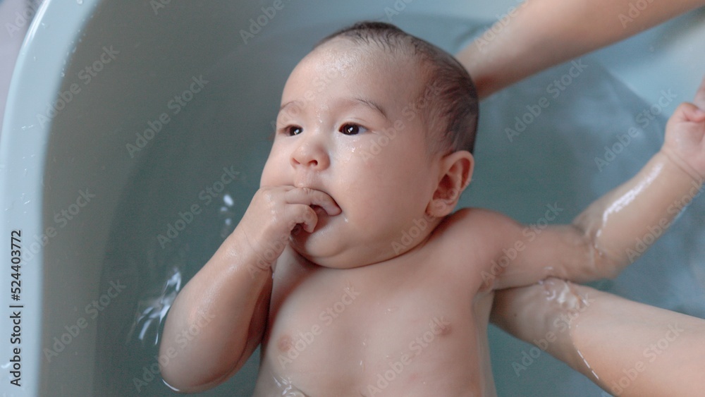 Top view of Cute baby having bath. Mother holds and bathes baby Top view of Cute baby having bath. Mother holds and bathes baby