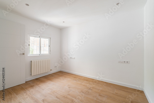 Empty room after renovation with window  white walls and wooden floor in new apartment