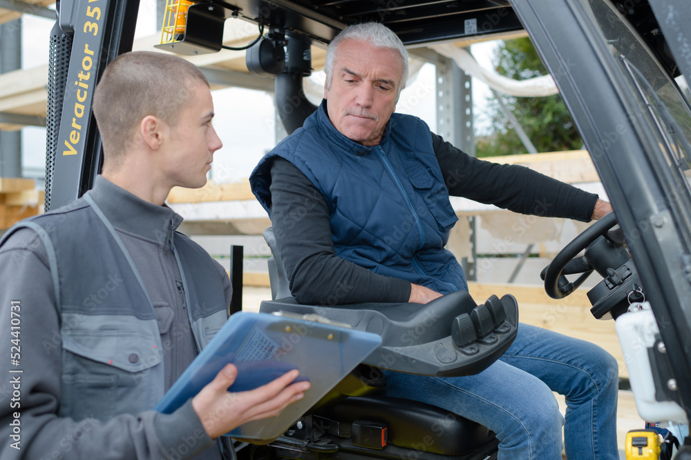 Man in forklift, colleague with clipboard Man in forklift, colleague with clipboard