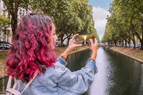 Happy girl travel blogger takes photos on her smartphone of the famous Konigsallee canal in the old town of Dusseldorf, Germany. Travel and sightseeing locations photo