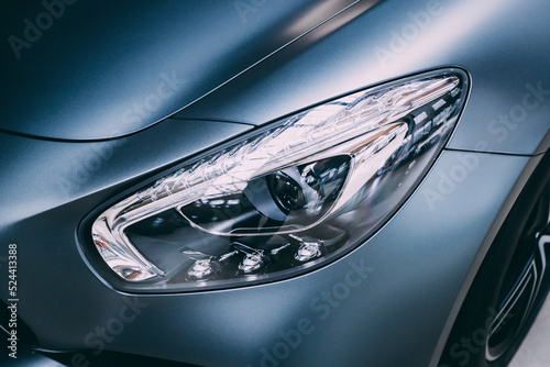 Close-up detailed view of the headlights of a luxury car in the garage. Halogen and xenon headlamp lighting and auto tuning systems