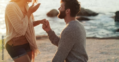 Romantic, romance and engagement proposal at the beach by boyfriend to surprise his girlfriend with a ring. Happy, in love and young man asking to marry a woman at sea on a summer evening sunset