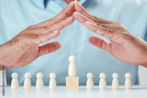 A man's hand protects a wooden peg doll that is like a corporate member. Risk and Crisis Prevention Planning taking care of business Finance and insurance, wooden puppets, wooden blocks.