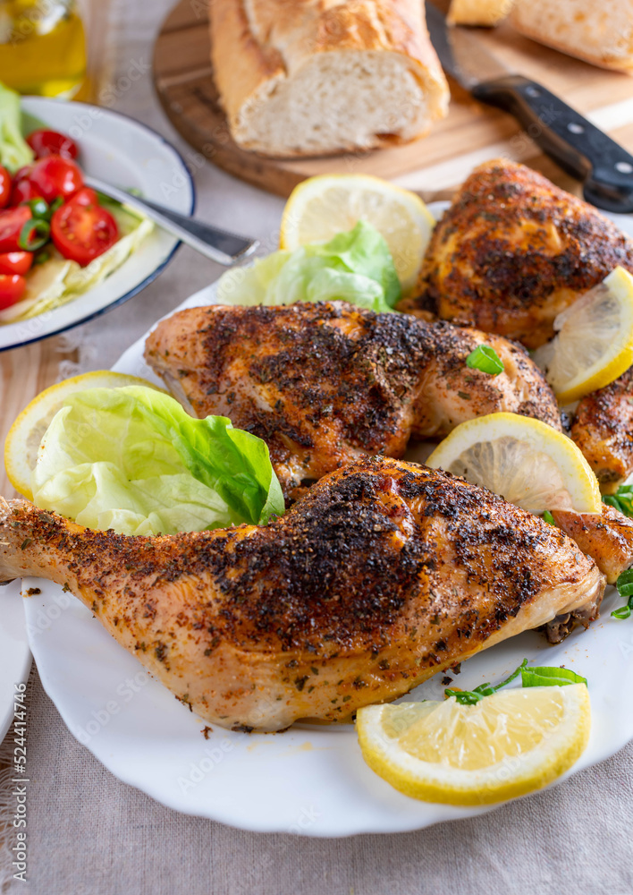 Baked chicken legs with salad and baguette on a dinner table Baked chicken legs with salad and baguette on a dinner table
