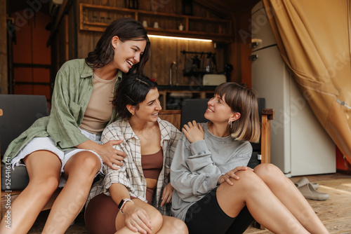 Three nice young caucasian women are discussing girlish topics camping on weekend. Brunettes wear T-shirt, shirt, shorts, sweatshirt. Leisure lifestyle and beauty concept.